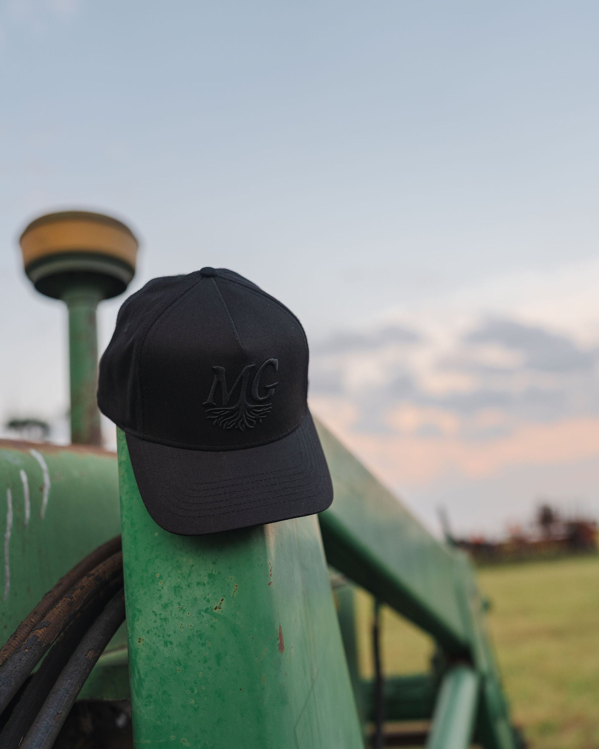 Black cap with 'Midwest Grown' logo on a green tractor against a sky background