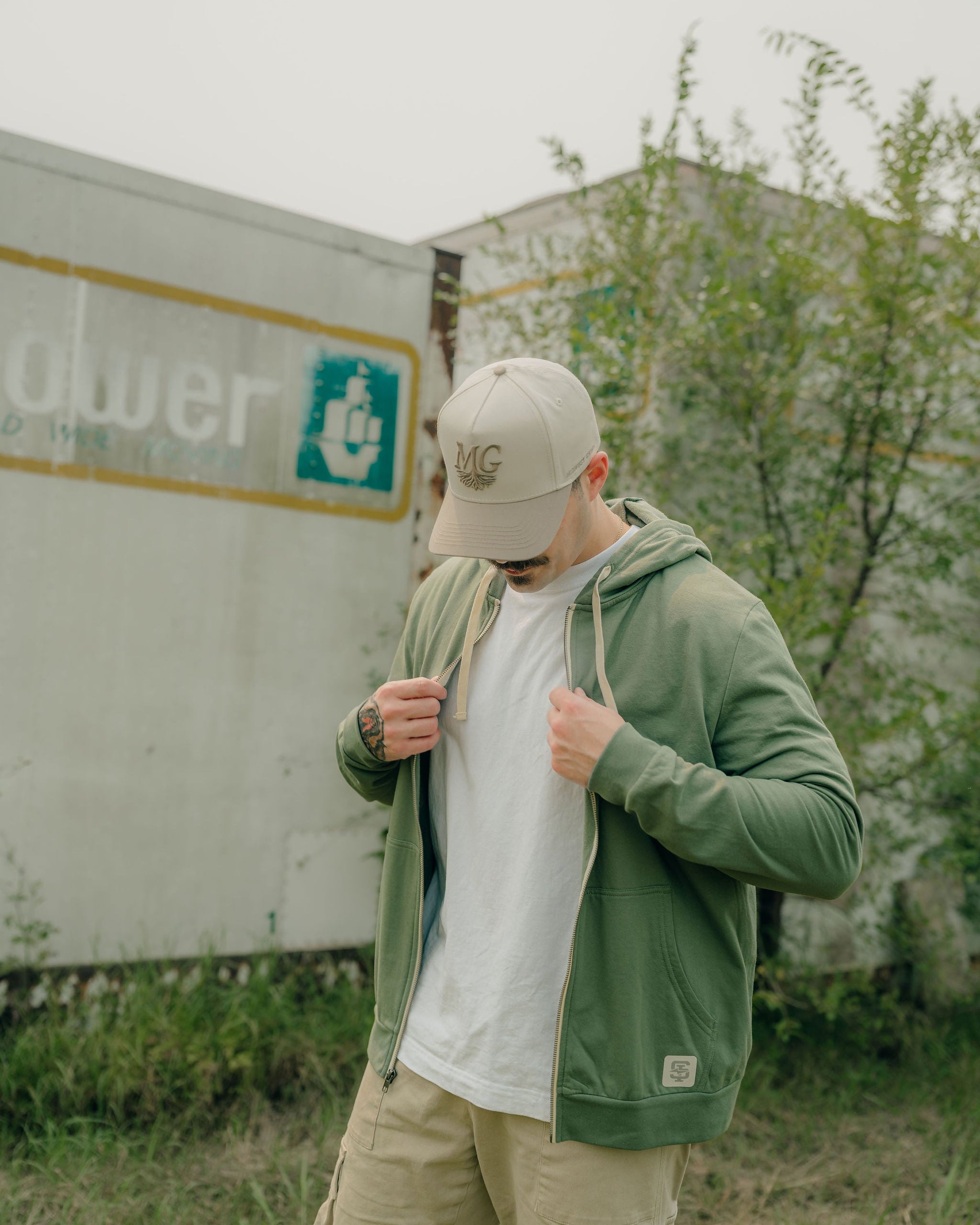 Man wearing a green hoodie and beige Midwest Grown cap in front of a truck with a visible brand logo.