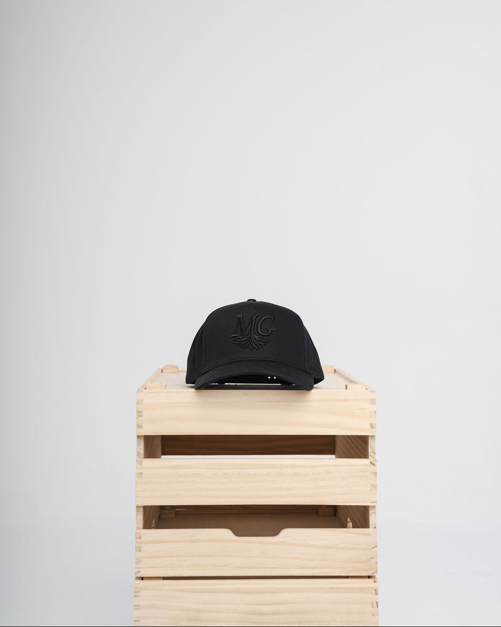 Black Midwest Grown cap on a wooden crate against a white background