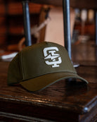 Green Standard Issue cap with a logo on a wooden surface