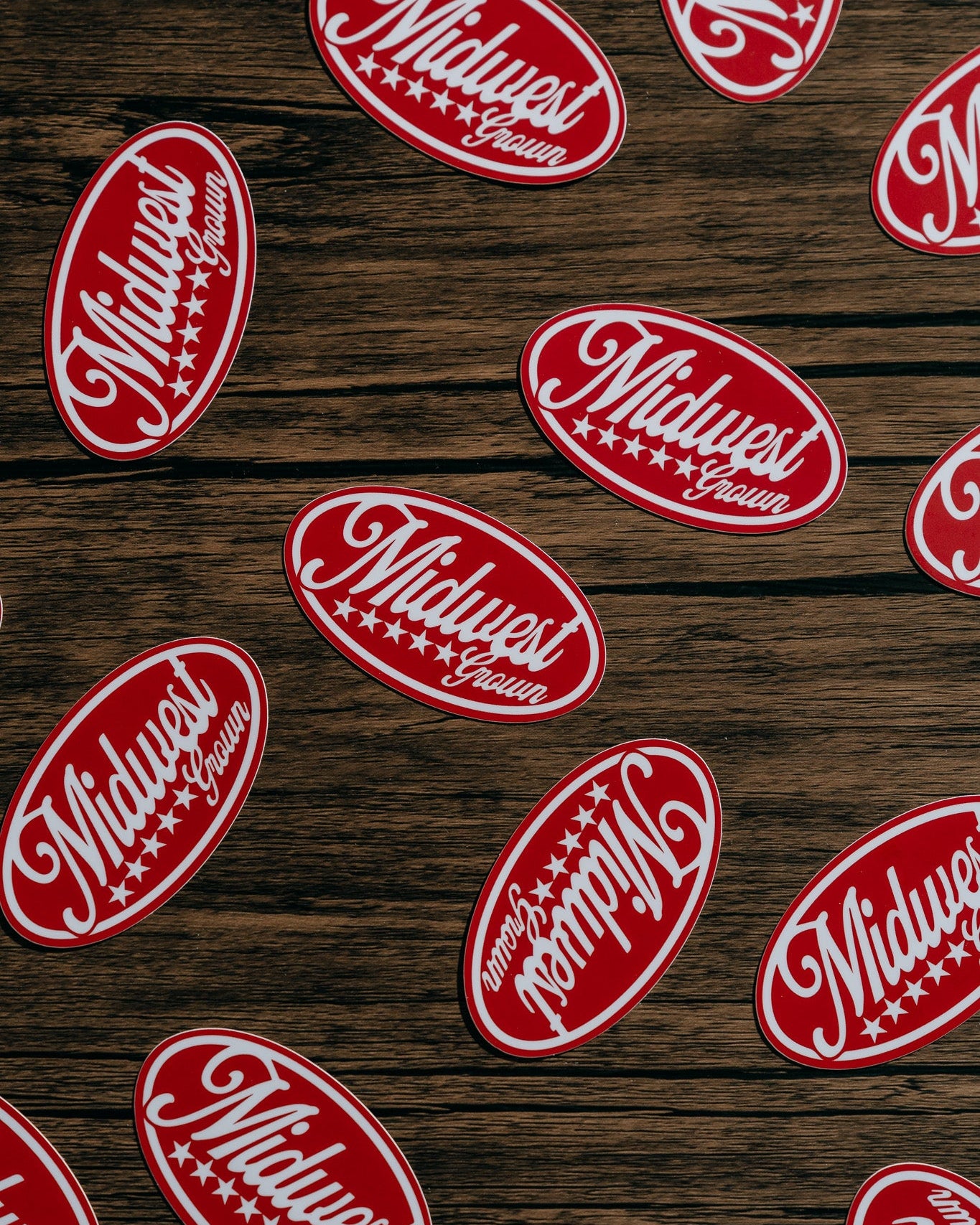 Red and white 'Midwest' logo stickers on a wooden surface