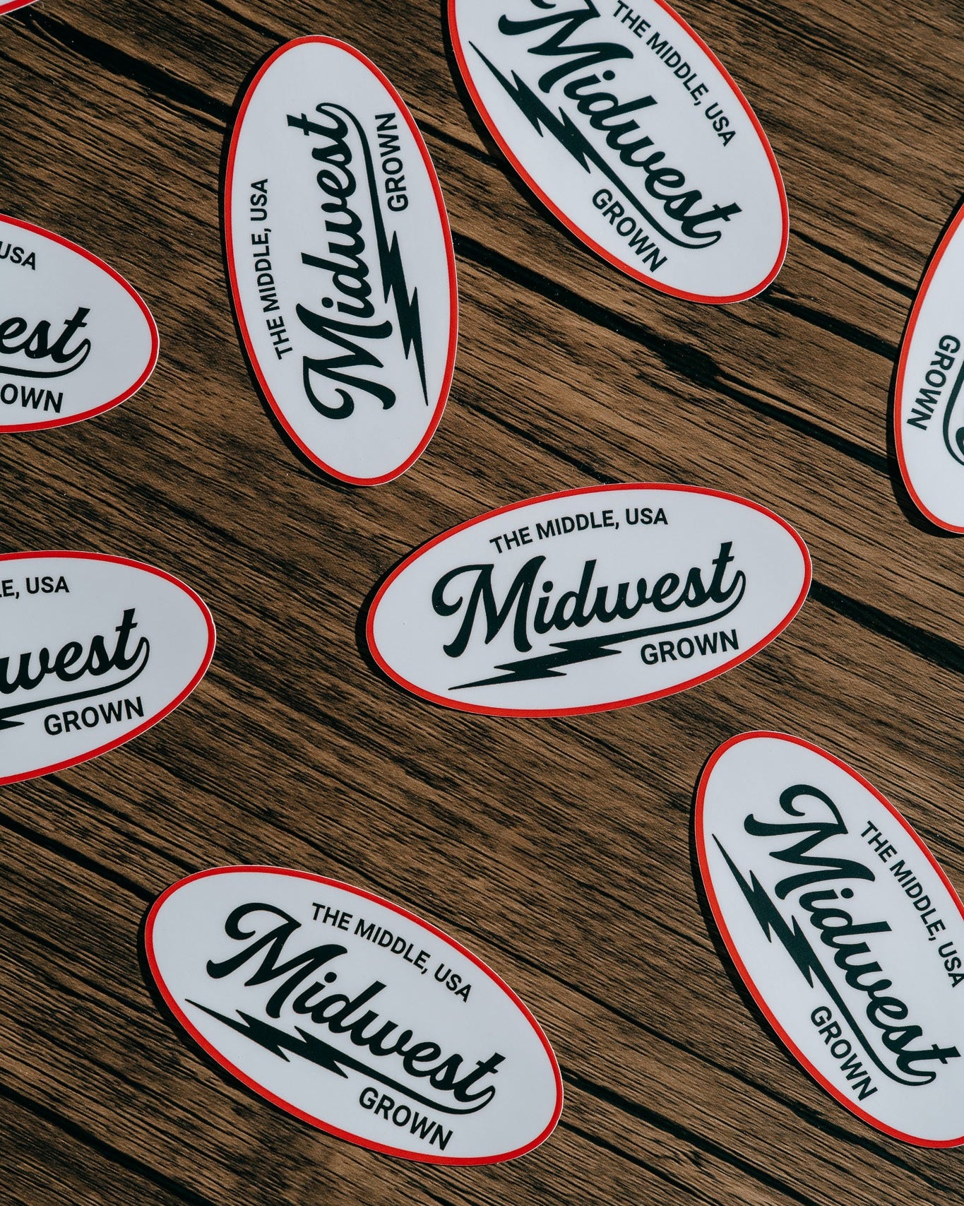 Multiple 'Midwest Grown' stickers on a wooden surface