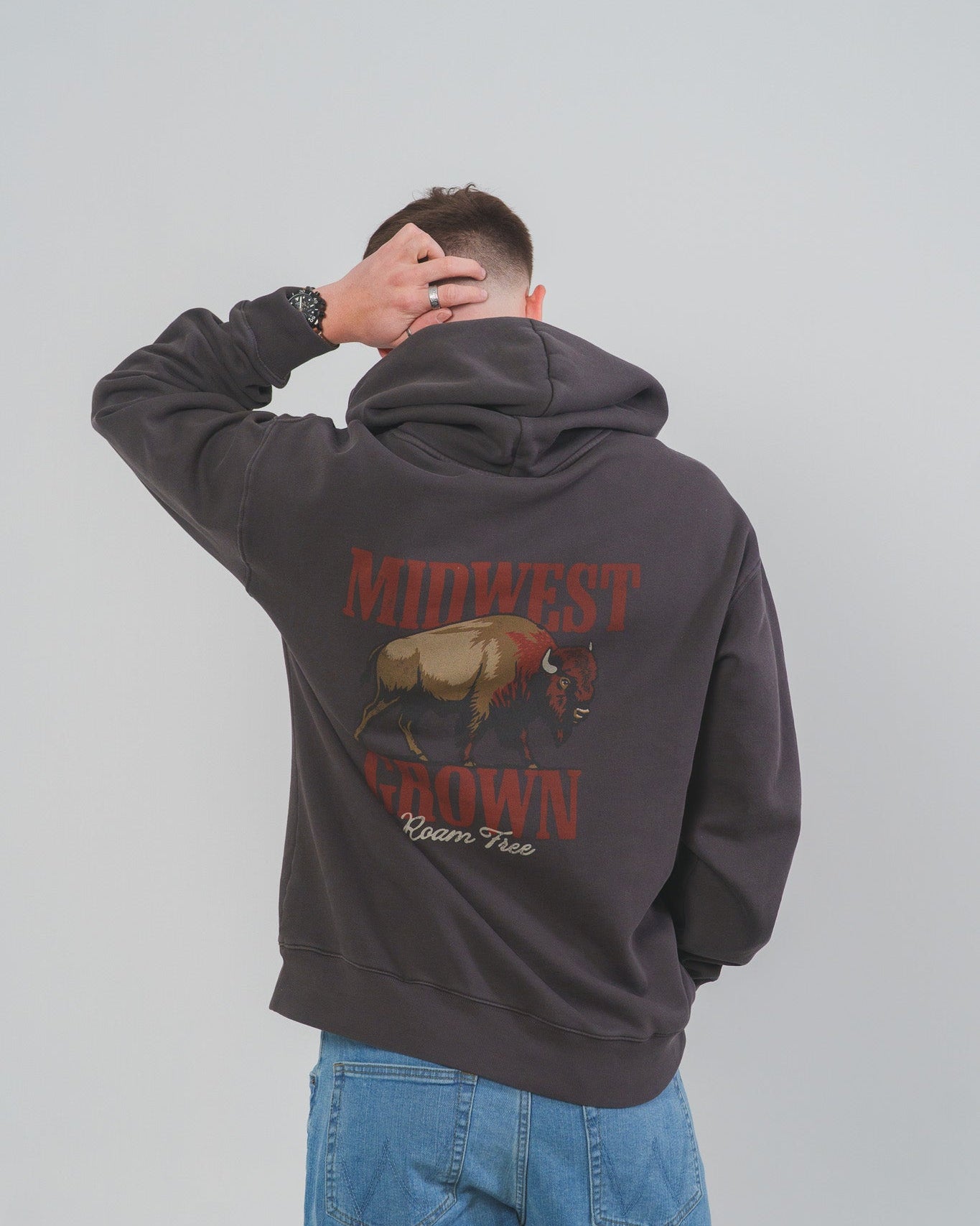 Person wearing a dark hoodie with 'Midwest Born' text and a Nison graphic on the back, standing against a plain background.