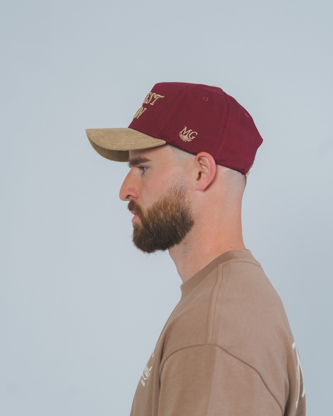 Man wearing a maroon cap with midwest grown logo on a light gray background