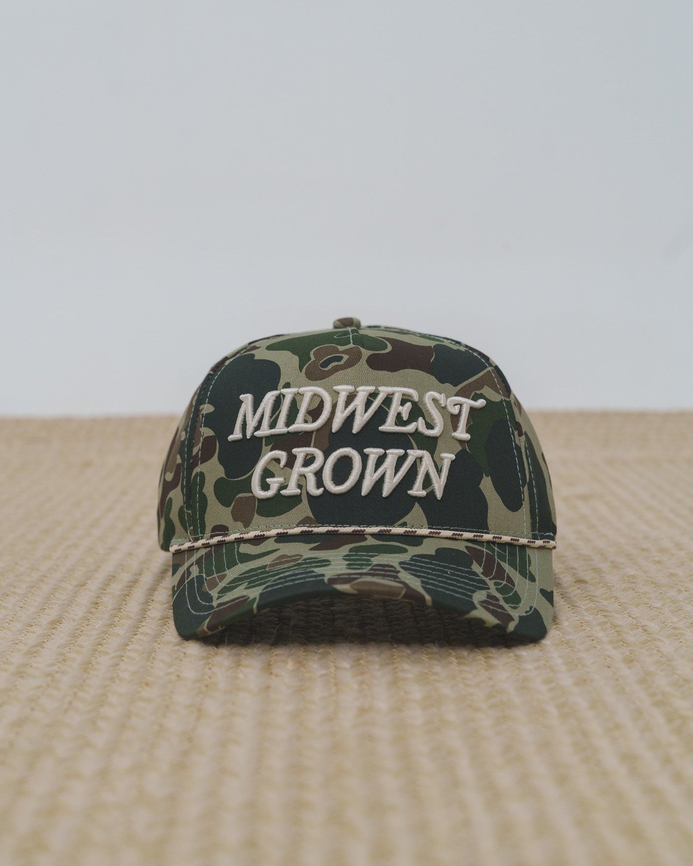 Duck Camouflage cap with 'Midwest Grown' text on a beige surface